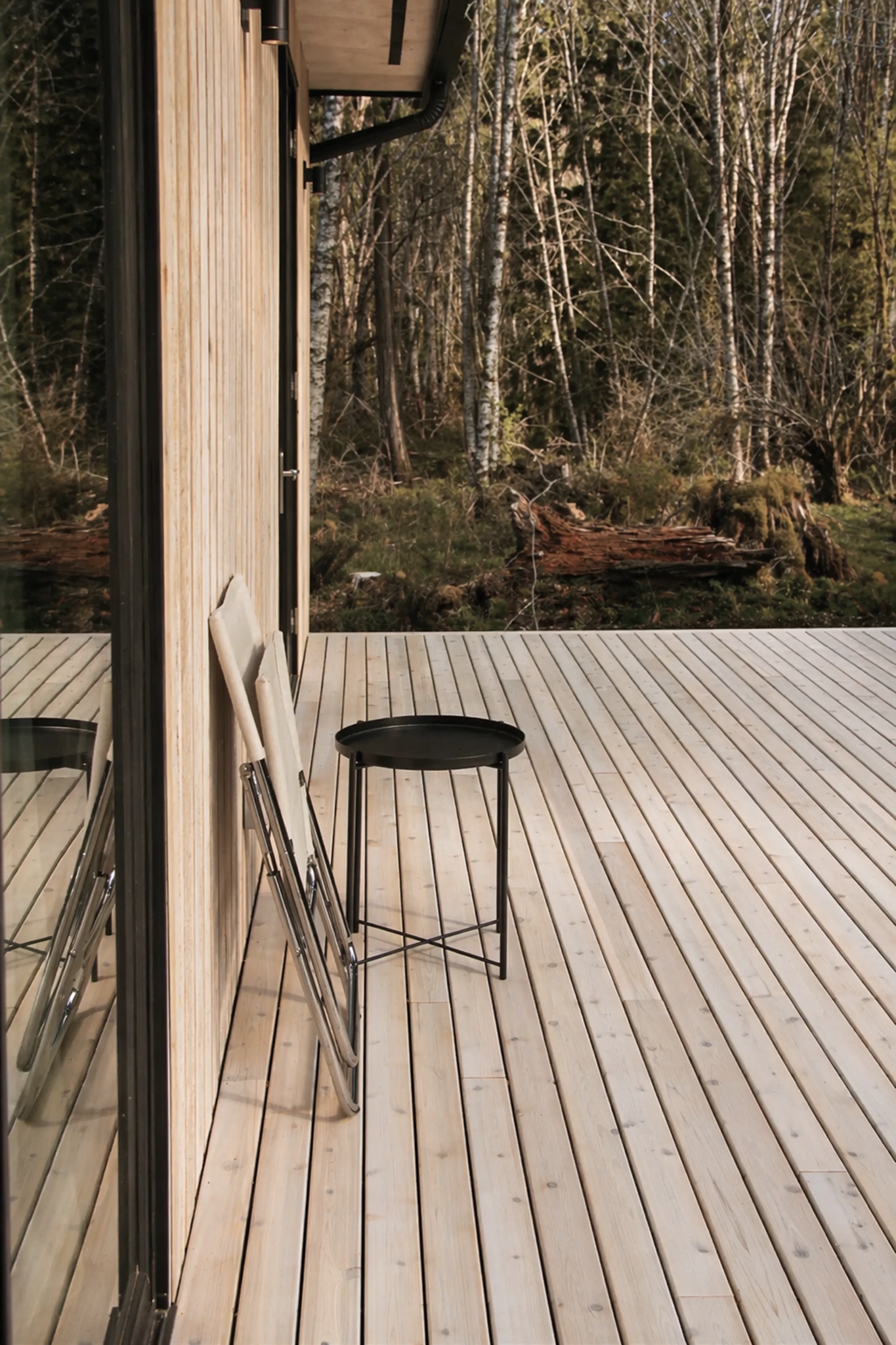 Norma cabin deck with chairs facing the surrounding alder forest
