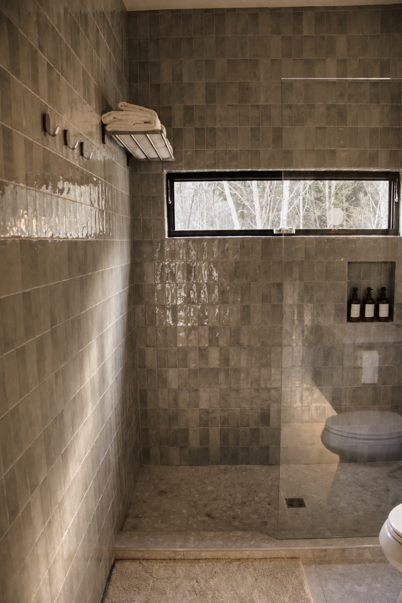 Walk-in tiled shower with a forest-facing window at Norma cabin
