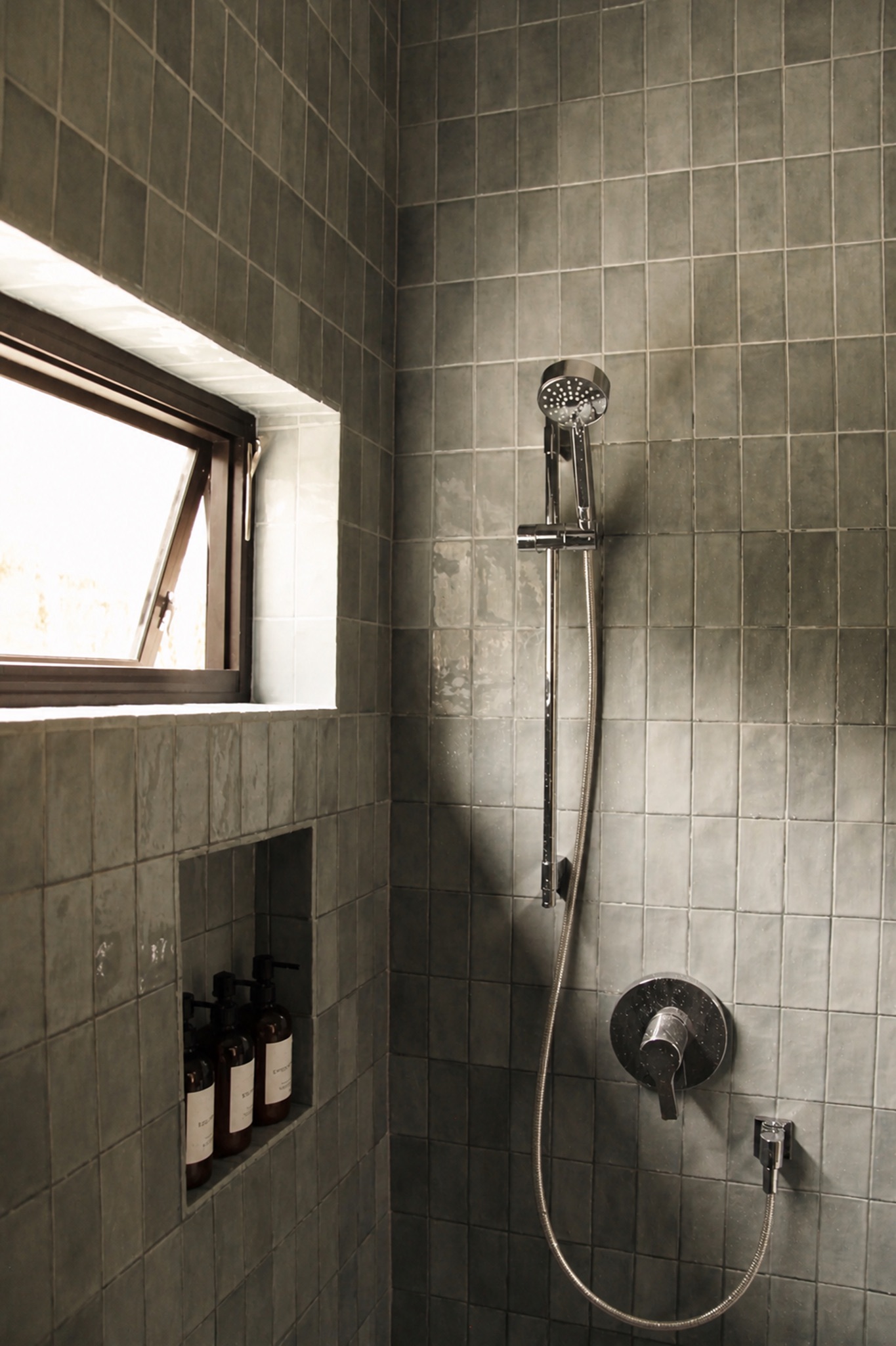 Tiled shower with a window and built-in toiletries at Norma cabin
