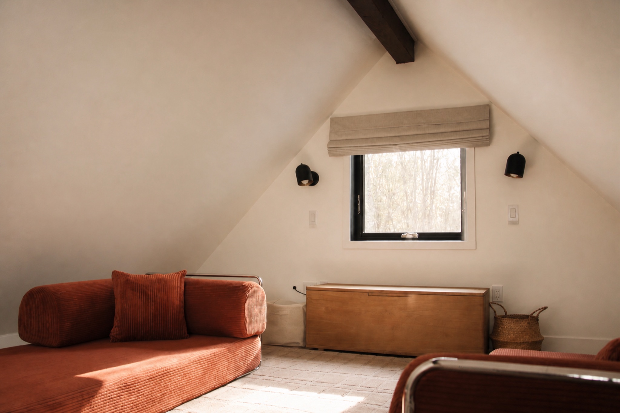 Sunlit loft at Norma cabin with rust-colored seating and a forest-facing window