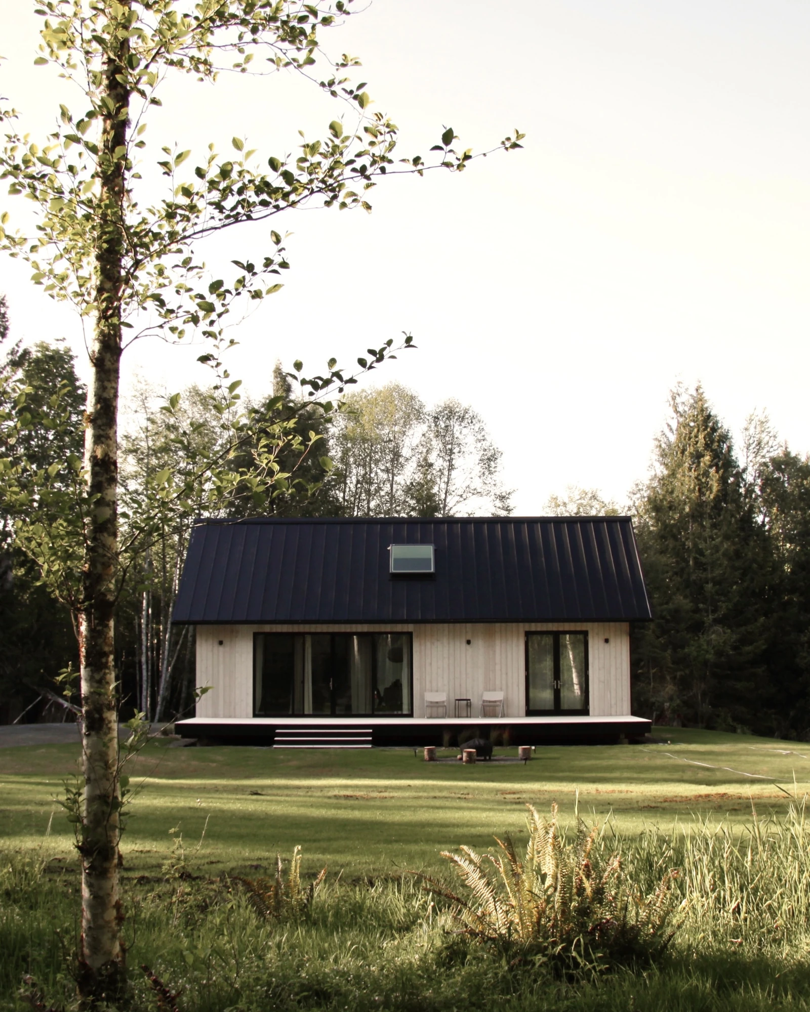 Norma cabin in a grassy clearing surrounded by alder and evergreen trees